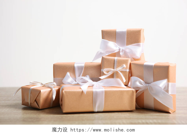 桌子上放着用金色纸包装的礼物礼物在金色包装上的轻背景和一个地方的文字。生日，圣诞节，新年，母亲节，三月八日，情人节